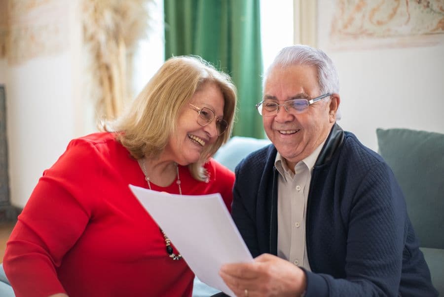 Couple de seniors souriant en consultant un document ensemble